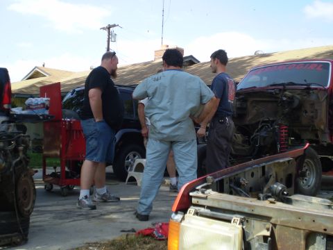 1969 Ford F-250 - Several men stand around a disassembled red truck, with parts and another vehicle nearby.