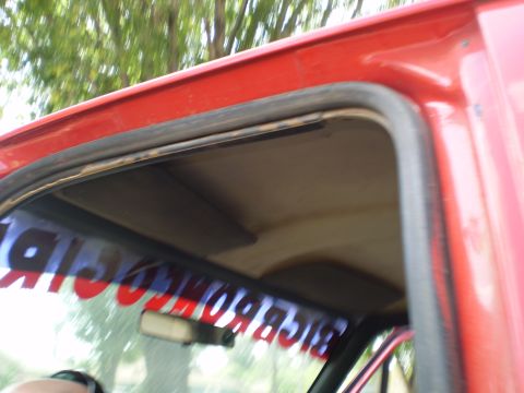 1969 Ford F-250 - Close-up of a red truck's interior, focusing on the headliner and a banner across the windshield.