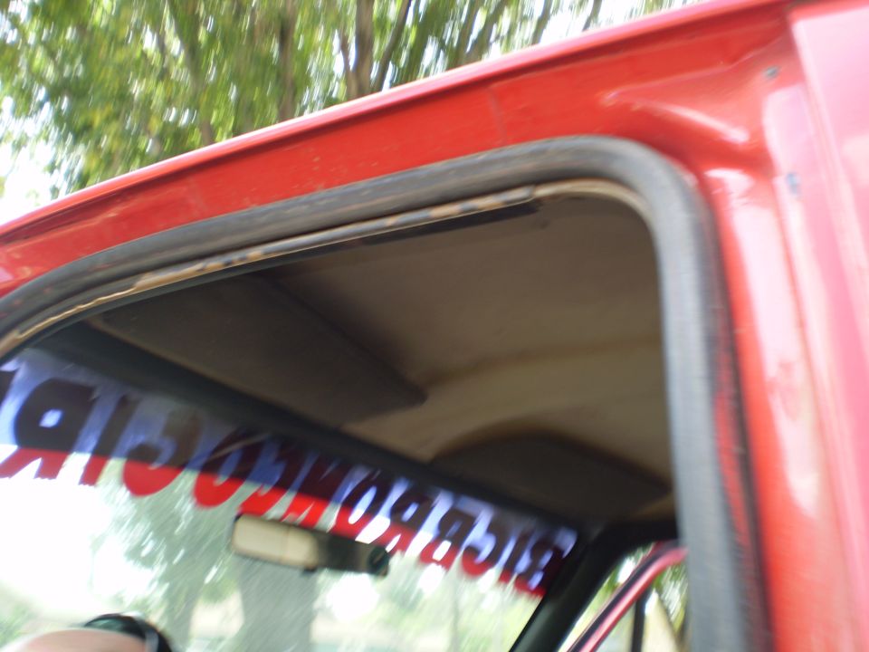 Red truck interior showing headliner and windshield banner. A rearview mirror is visible