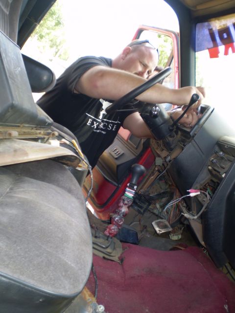 1969 Ford F-250 - A man is working on the dashboard and steering column of a truck, with exposed wiring visible.