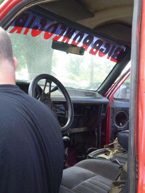1969 Ford F-250 - The interior of a red truck shows a custom steering wheel and a banner across the windshield reading "BIGBOMBS".