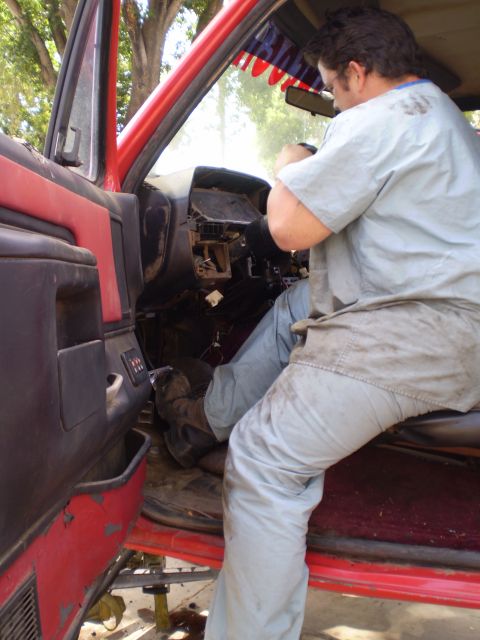 1969 Ford F-250 - A person is working on the interior of a red truck, with the dashboard removed.