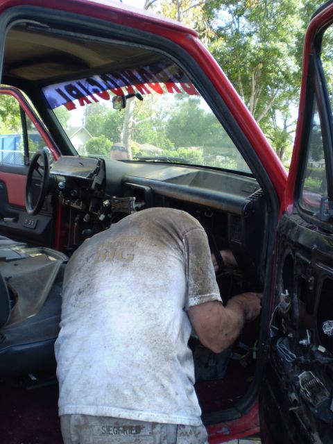 1969 Ford F-250 - Mechanic works on the dashboard of a red truck, with a banner across the windshield.
