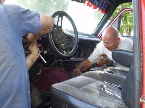 1969 Ford F-250 - Two men are working on the dashboard of a red truck, with tools visible on the seats.