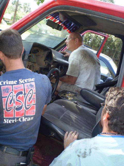 1969 Ford F-250 - Three men are inside the cab of a red truck, appearing to work on the dashboard and interior components.