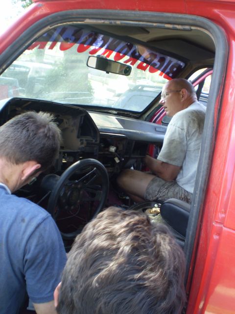 1969 Ford F-250 - Three people are inside the cab of a red truck, appearing to work on the dashboard and steering column.