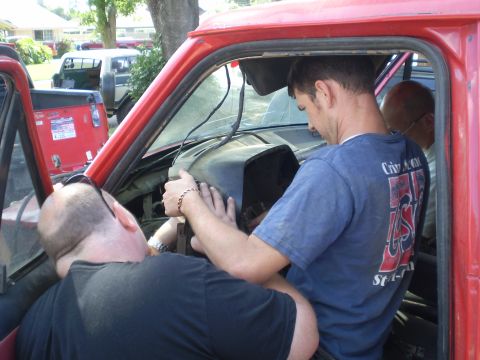1969 Ford F-250 - Mechanics are working on the interior of a red truck, with another vehicle in the background.