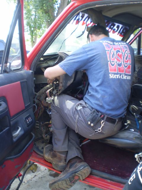 1969 Ford F-250 - A person is working on the interior wiring of a vehicle, with the dashboard removed.