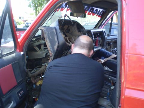 1969 Ford F-250 - The dashboard and wiring are exposed as work is done inside the cab of a red truck.