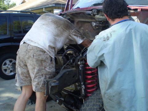 1969 Ford F-250 - Mechanics are actively working on the engine of a red vehicle, with a black SUV visible in the background.