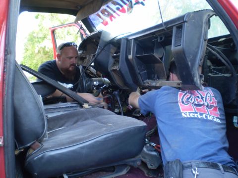 1969 Ford F-250 - Two mechanics are seen working on the interior of a red truck, possibly during a repair or modification.