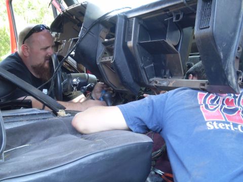 1969 Ford F-250 - Two men are working on the interior of a vehicle, with the dashboard disassembled.