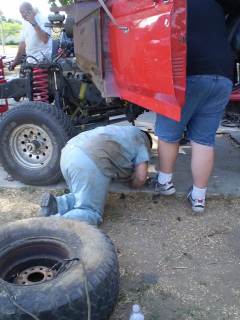 1969 Ford F-250 - Mechanics are working on the frame and suspension of a vehicle, with a spare tire nearby.
