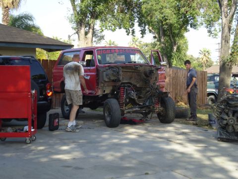 1969 Ford F-250 - A red pickup truck is being worked on, with its front end disassembled and a sticker on the windshield.