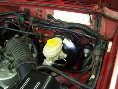 1991 Jeep Comanche - Engine bay of a 1991 Jeep Comanche, the brake booster and master cylinder assembly.