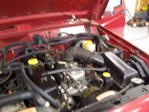 1991 Jeep Comanche - The engine compartment of a red Jeep is shown with various components and wiring visible.