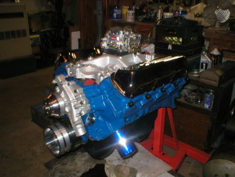 1978 Ford Bronco - A V8 engine, painted blue with chrome accents, is mounted on a red engine stand in a workshop.