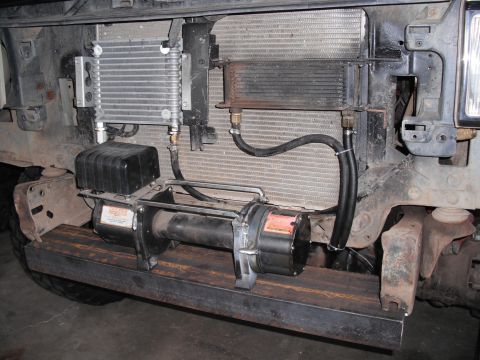 1991 Ford Bronco - A winch is installed on a custom metal plate, positioned in front of the vehicle's radiator and oil cooler assembly.