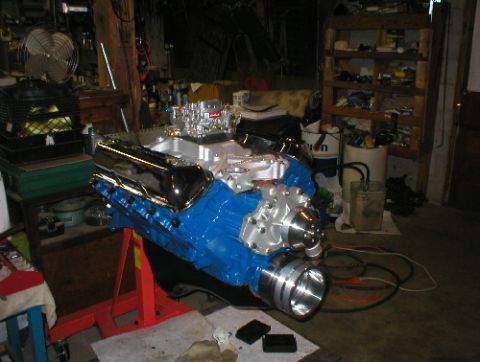 1978 Ford Bronco - A blue V8 engine with chrome valve covers and a carburetor sits on an engine stand in a workshop.