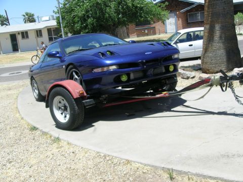 1995 Ford Probe - A blue 1995 Ford Probe is being towed on a trailer, showing its distinctive front-end styling.