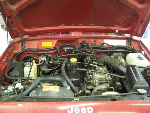1991 Jeep Comanche - Engine compartment of a red Jeep truck, showing the engine and various components under the hood.