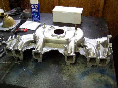 1991 Jeep Comanche - An aluminum intake manifold sits on a workbench next to a can of gasket remover and other tools.