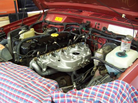 1991 Jeep Comanche - The engine bay of a red Jeep Comanche shows various mechanical components and a plaid cloth draped over some parts.