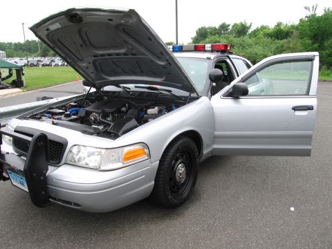 1991 Ford LTD Crown Victoria - silver Ford Crown Victoria police interceptor sits with its hood raised, exposing the engine bay, in a parking lot beside another light-bar…