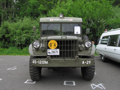 1991 Ford LTD Crown Victoria - Front view of an olive-drab military ambulance truck marked AMBULANCE with a grille guard, headlights and 45-120M / A-29 markings.
