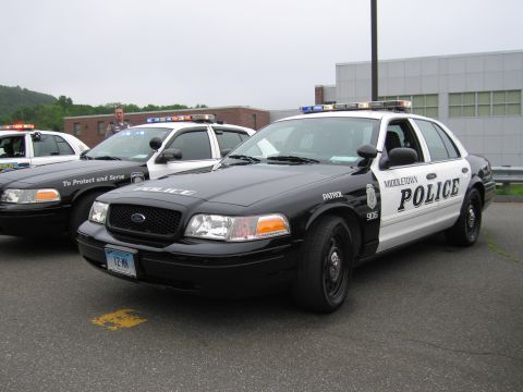 1991 Ford LTD Crown Victoria - black-and-white Middletown Police Ford Crown Victoria patrol car marked To Protect and Serve, parked beside other cruisers.