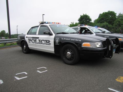 1991 Ford LTD Crown Victoria - black-and-white Avon Police Ford Crown Victoria cruiser shown in side profile, marked To Protect and Serve, on pavement.