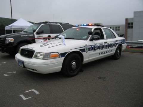 1991 Ford LTD Crown Victoria - white East Hartford Police Traffic-unit Ford Crown Victoria cruiser with blue striping, parked beside a dark police SUV.