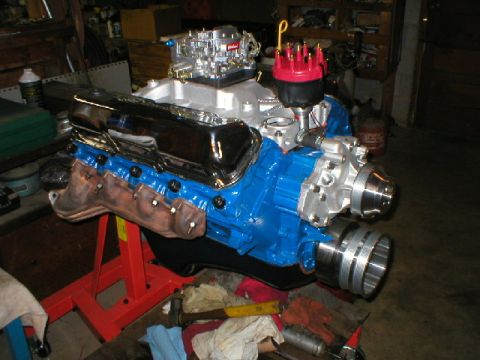 1978 Ford Bronco - Freshly rebuilt Ford V8 short block painted Ford blue on a red engine stand in a garage, fitted with a polished aluminum intake manifold, c…