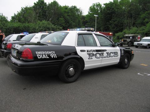 1991 Ford LTD Crown Victoria - black-and-white Ford Crown Victoria police cruiser marked 'Avon Police' and 'Emergency Dial 911', parked at an outdoor event.