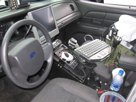 1991 Ford LTD Crown Victoria - Interior of a Ford police cruiser showing the steering wheel, a mounted computer display, keyboard, radio and console equipment.