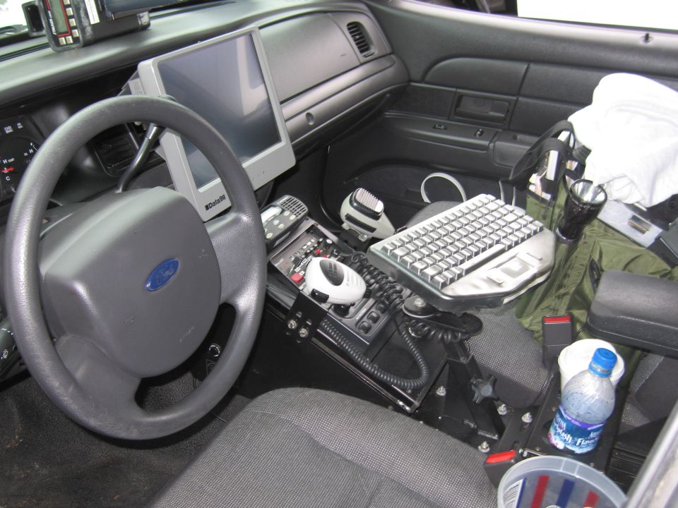 Police car interior with Ford steering wheel, mounted laptop and radio gear