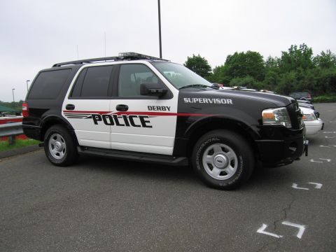 1991 Ford LTD Crown Victoria - black-and-white Ford Expedition marked 'Derby Police Supervisor' with red accent stripe, parked outdoors.
