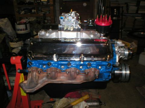 1978 Ford Bronco - A freshly rebuilt Ford V8 sits on a red engine stand in a garage, painted Ford blue with polished chrome valve covers, a polished aluminum…