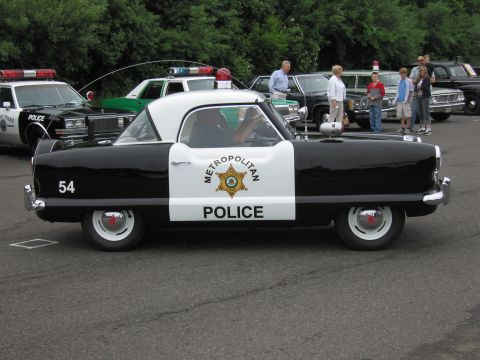 1991 Ford LTD Crown Victoria - small black-and-white Nash Metropolitan styled as a 'Metropolitan Police' car number 54 at a police vehicle show.