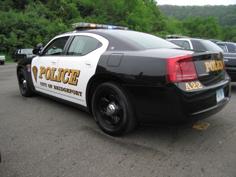 1991 Ford LTD Crown Victoria - black-and-white Dodge Charger lettered 'Police City of Bridgeport A22', parked at an outdoor police car event.