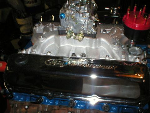 1978 Ford Bronco - Top-down view of a Ford V8 engine with a polished aluminum intake manifold, a four-barrel carburetor with brass linkage and blue fittings,…