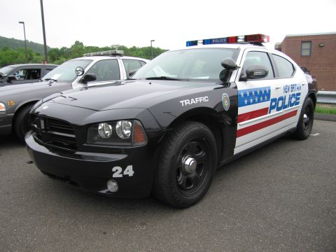 1991 Ford LTD Crown Victoria - black-and-white Dodge Charger with American-flag graphics marked 'New Britain Police Traffic 24', parked outdoors.