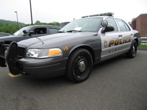 1991 Ford LTD Crown Victoria - gray Ford Crown Victoria police interceptor marked 'POLICE Simsbury' with a roof light bar and push bumper, parked at a lot.