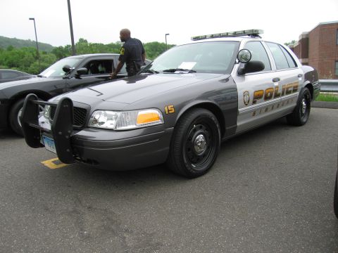 1991 Ford LTD Crown Victoria - gray Ford Crown Victoria police car marked 'POLICE Simsbury' with a push bumper and roof lights, a man standing alongside.