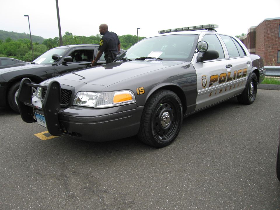 Gray Ford Crown Victoria police sedan, Simsbury Police, with man standing beside it