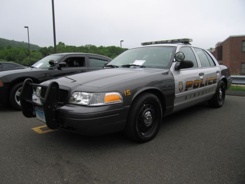 1991 Ford LTD Crown Victoria - Front three-quarter view of a gray Ford Crown Victoria 'POLICE Simsbury' interceptor with push bumper and roof light bar.