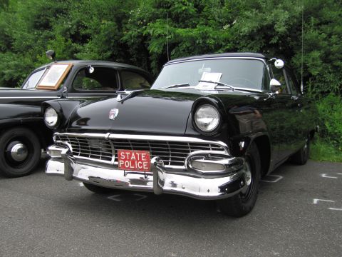 1991 Ford LTD Crown Victoria - Front view of a black mid-1950s Ford with chrome grille, hood ornament and a red 'STATE POLICE' license plate.