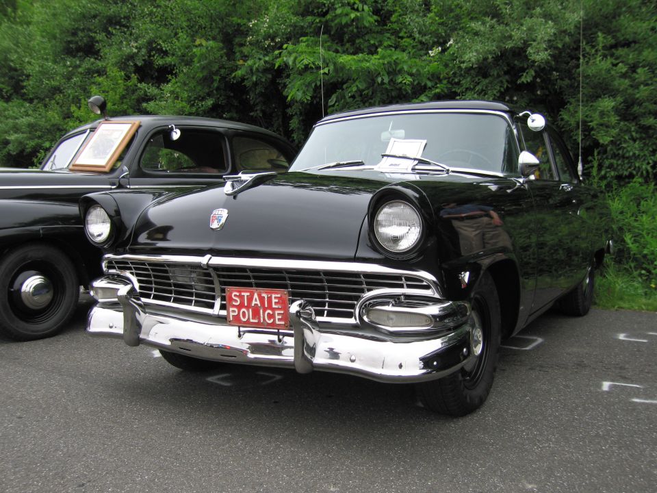 Black 1956 Ford Fairlane front with chrome grille and red State Police plate