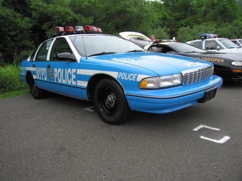 1991 Ford LTD Crown Victoria - light-blue Chevrolet Caprice marked 'NYPD POLICE' with a roof light bar, parked at a vehicle show.
