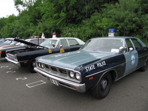 1991 Ford LTD Crown Victoria - light-blue State Police full-size sedan with a roof beacon parked beside other classic police cars on asphalt.